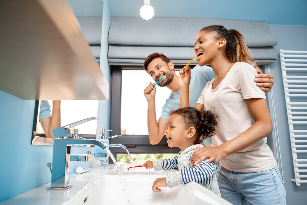 famille qui se brosse les dents avec brosse à dents dans la salle de bain